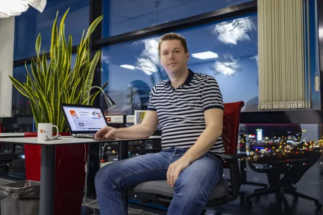Александр Евстигнеев за рабочим столом в офисе AVE Design Studio вечером, за окном огни города
